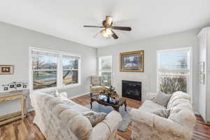 Living room with a tile fireplace, wood finished floors, plenty of natural light, and a ceiling fan