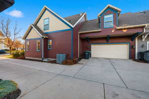 View of side of property with a shingled roof, concrete driveway, and a garage