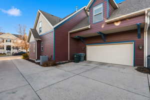 View of home's exterior with roof with shingles, driveway, and a garage