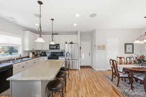 Kitchen featuring pendant lighting, a breakfast bar area, black appliances, a chandelier, and a center island