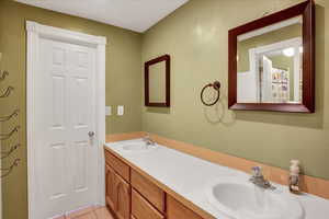 Bathroom featuring double vanity, light tile patterned floors, and curtained shower