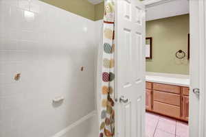 Bathroom with light tile patterned flooring and shower / bathtub combination with curtain