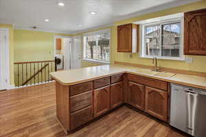 Kitchen with dishwasher, light countertops, light wood-type flooring, crown molding, and recessed lighting
