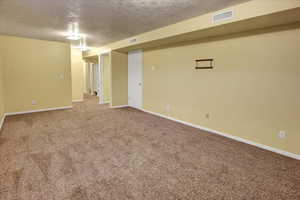 Spare room with a textured ceiling and carpet