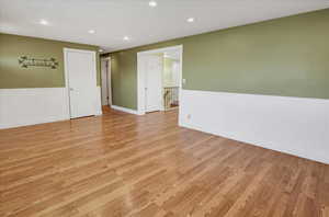 Spare room with a wainscoted wall, light wood-style flooring, and recessed lighting
