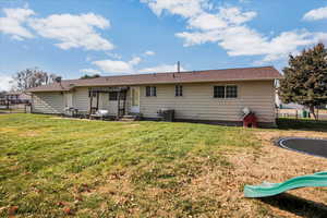 Rear view of property featuring a yard, a patio, and a trampoline