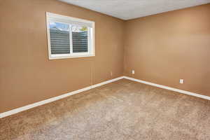 Carpeted empty room with baseboards and a textured ceiling