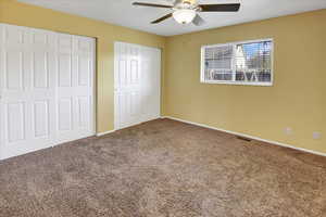 Unfurnished bedroom featuring two closets, carpet floors, and ceiling fan