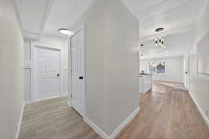 Hall with light wood-type flooring and ornamental molding