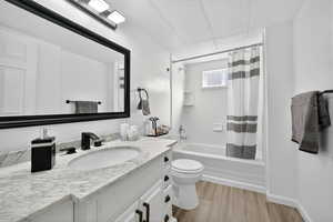 Full bath featuring shower / tub combo with curtain, vanity, a textured ceiling, and light wood-style floors