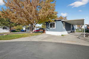 View of property exterior featuring an attached carport and concrete driveway