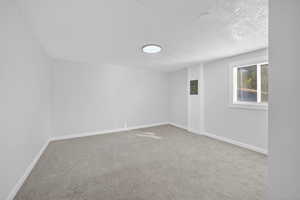 Empty room with a textured ceiling, light colored carpet, and electric panel