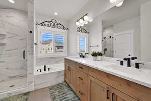 Bathroom featuring double vanity, a marble finish shower, and a garden tub