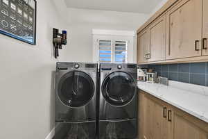 Laundry room with washer and clothes dryer and cabinet space
