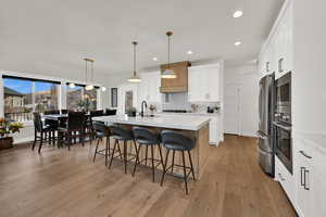 Kitchen featuring white cabinets, pendant lighting, recessed lighting, a center island with sink, and stainless steel appliances
