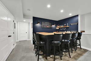Indoor dry bar featuring recessed lighting, dark cabinetry, and wooden counters