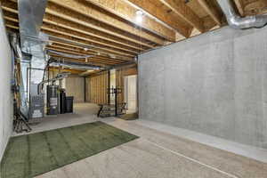 Unfinished below grade area featuring water heater, a water softener system, and heating unit