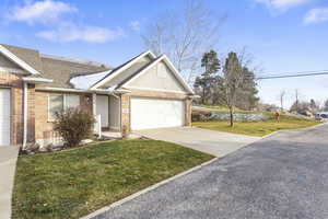 Ranch-style home featuring brick siding, a front lawn, concrete driveway, an attached garage, and a shingled roof
