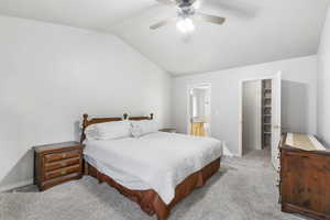 Carpeted bedroom with vaulted ceiling, a ceiling fan, and ensuite bathroom