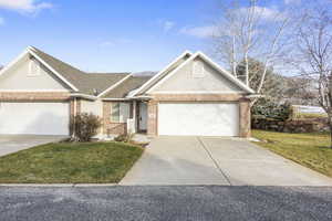 Single story home with brick siding, driveway, a garage, and a front lawn
