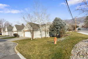 View of front of home featuring a front yard, concrete driveway, brick siding, and roof with shingles