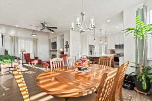 Dining area featuring a fireplace, a textured ceiling, a ceiling fan, dark wood finished floors, and recessed lighting