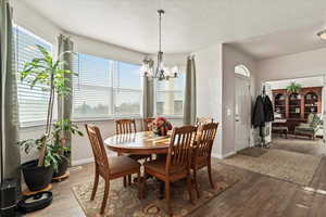 Dining room featuring wood finished floors, a textured ceiling, and a chandelier