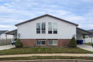 View of property exterior featuring a carport, driveway, and brick siding