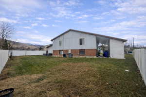 Back of house featuring a fenced backyard, brick siding, and a mountain view