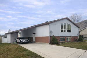View of side of property featuring brick siding, driveway, and an attached carport