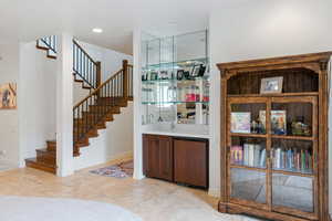 Indoor wet bar featuring stone tile floors and baseboards