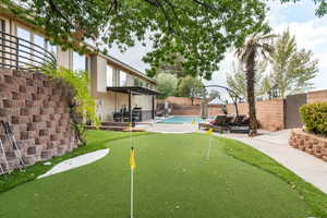 Fenced backyard featuring an area to practice putting, a patio area, a pergola, and an outdoor living space