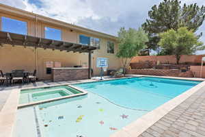 View of swimming pool with a patio area, a pool with connected hot tub, and a pergola