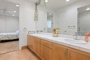 Full bath with double vanity, light tile patterned floors, light colored carpet, recessed lighting, and a tile shower
