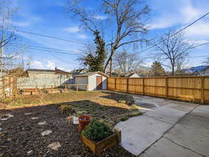 Fenced backyard featuring a shed