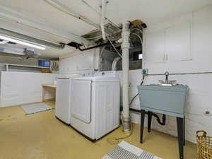 Washroom featuring unfinished concrete flooring, washing machine and dryer, and cabinet space