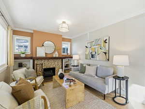 Living room featuring crown molding, wood finished floors, and a fireplace