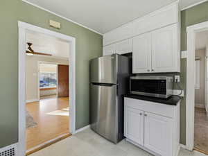 Kitchen featuring dark countertops, white cabinets, appliances with stainless steel finishes, crown molding, and ceiling fan