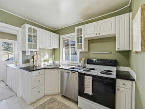 Kitchen featuring glass insert cabinets, electric range, white cabinets, and stainless steel dishwasher