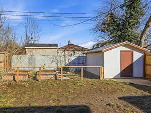 Fenced backyard featuring a vegetable garden and a storage unit