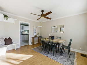 Dining room with light wood-style flooring, crown molding, and ceiling fan