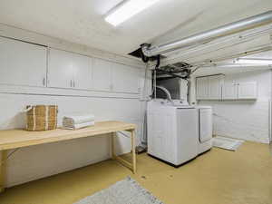 Washroom with cabinet space, finished concrete flooring, and separate washer and dryer