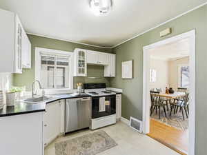 Kitchen featuring electric range oven, white cabinets, glass insert cabinets, dishwasher, and ornamental molding