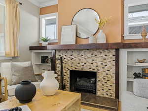 Detailed view of a tile fireplace, wood finished floors, and crown molding
