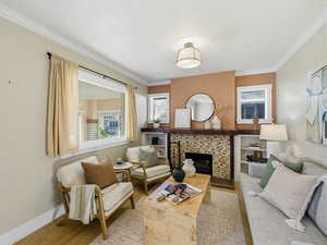 Living room featuring wood finished floors, a fireplace, and ornamental molding