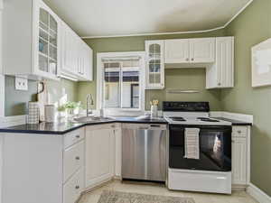 Kitchen with glass insert cabinets, range with electric cooktop, dishwasher, white cabinetry, and light tile patterned floors