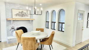 Dining room featuring a brick fireplace, light wood-style flooring, a chandelier, and recessed lighting