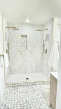 Bathroom with a marble finish shower, a textured ceiling, and vanity