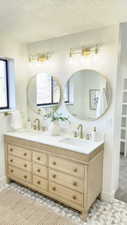 Full bathroom with double vanity and a textured ceiling