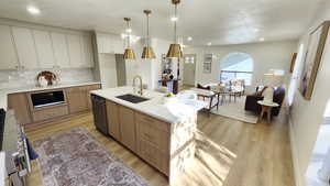 Kitchen with light stone countertops, decorative light fixtures, tasteful backsplash, light wood-style floors, and recessed lighting